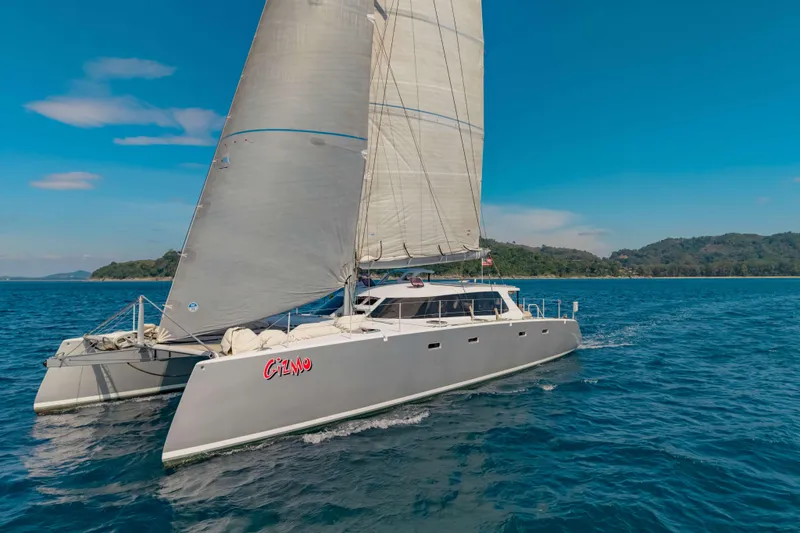 Gizmo Yacht Photos Pics Sailing catamaran Morrelli & Melvin 65 custom, 2012, cruising on blue ocean near lush coastline.