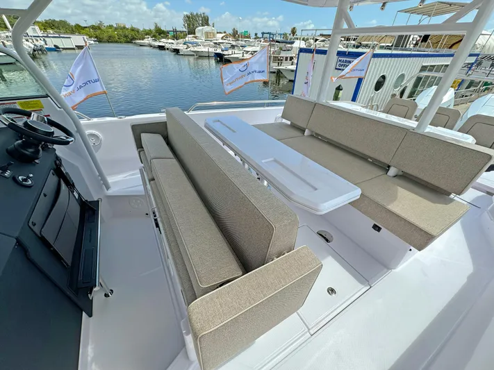  Yacht Photos Pics 2025 Axopar 37 Sun Top boat interior with beige seating and table, docked at marina.