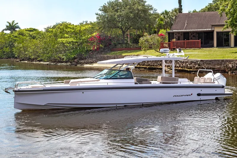 Yacht Photos Pics 2025 Axopar 37 Sun Top boat on a serene waterway near a lush, green landscape.