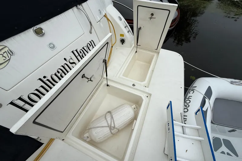 Houligan's Haven Yacht Photos Pics 2004 Cruisers 370 Express boat with open storage compartments and docked inflatable dinghy.