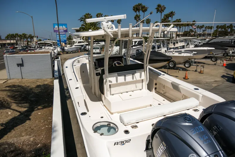 Elixir Yacht Photos Pics 2023 Robalo R302 Center Console boat docked at a marina with palm trees.