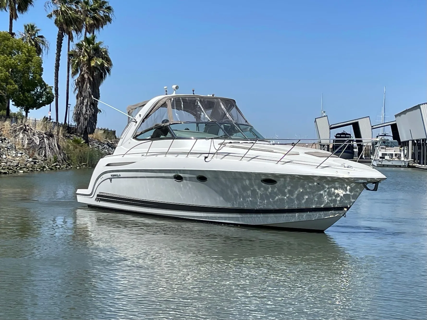 2003 Formula 37 PC yacht cruising on a calm waterway with palm trees in the background.