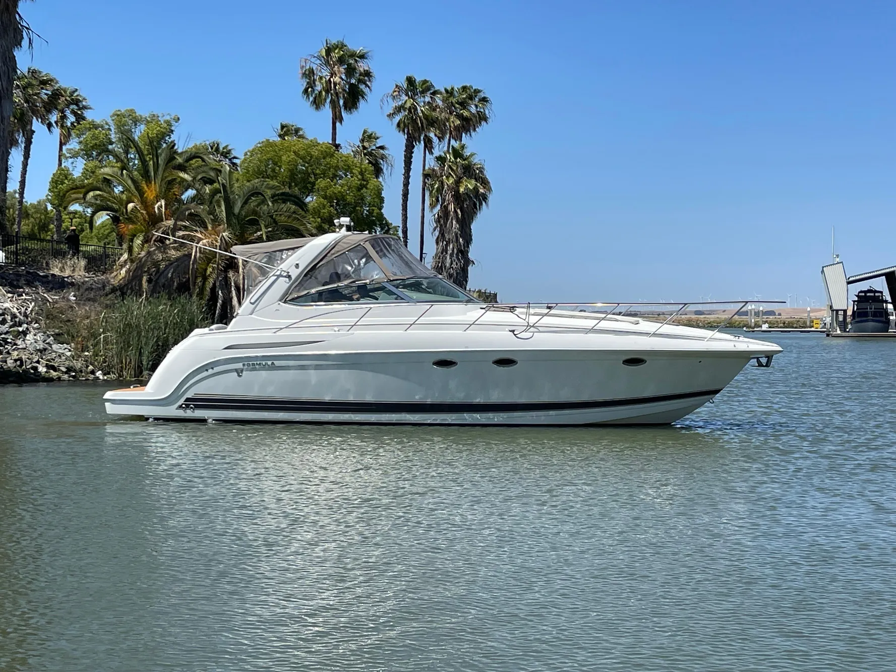 2003 Formula 37 PC yacht on calm water with palm trees in the background.