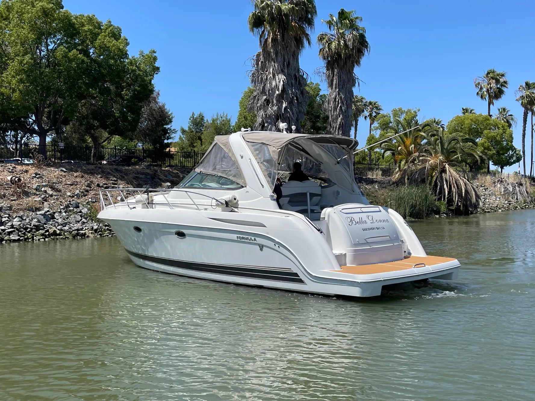 2003 Formula 37 PC yacht cruising on a serene lake with lush greenery.