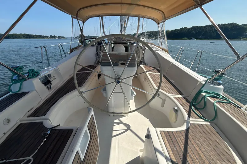 Table 4 Two Yacht Photos Pics 2004 Beneteau Oceanis 423 sailboat cockpit with steering wheel, docked on calm water.