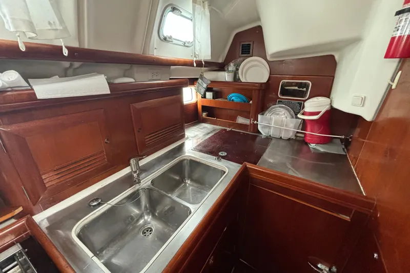 Table 4 Two Yacht Photos Pics Galley kitchen of 2004 Beneteau Oceanis 423 sailboat with wooden cabinetry and stainless steel sink.