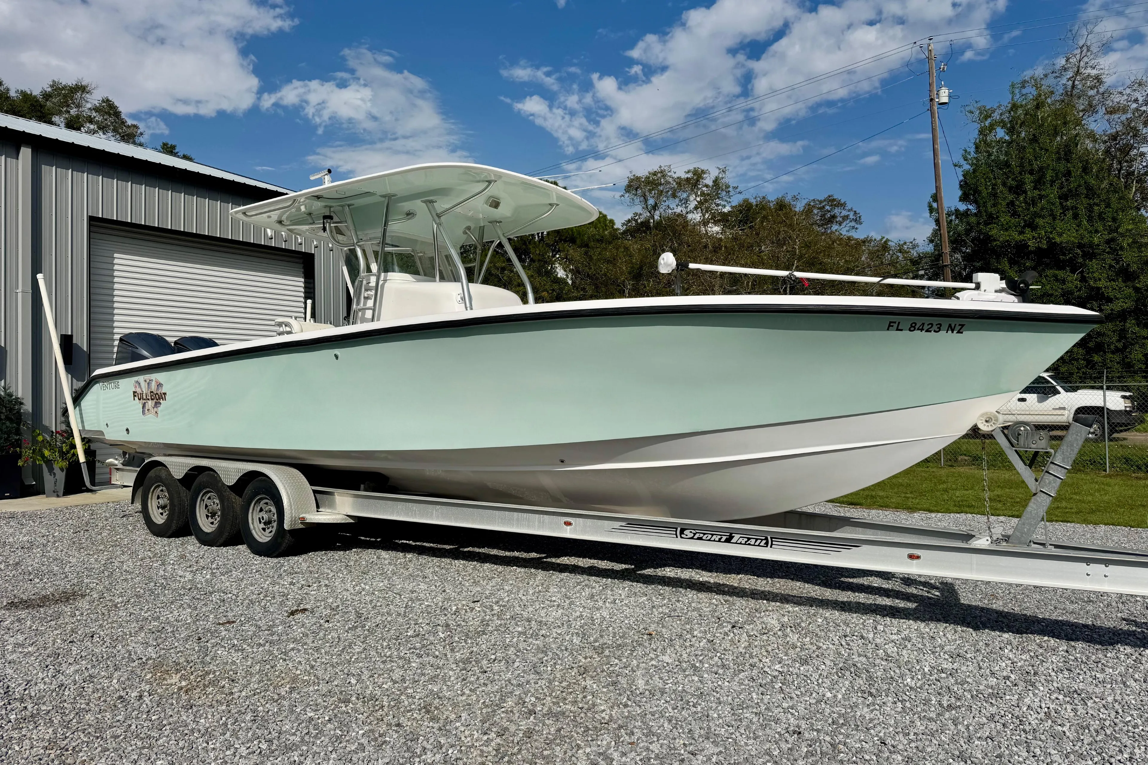 2010 Venture 34 Tournament boat on trailer, parked outdoors near a metal building.