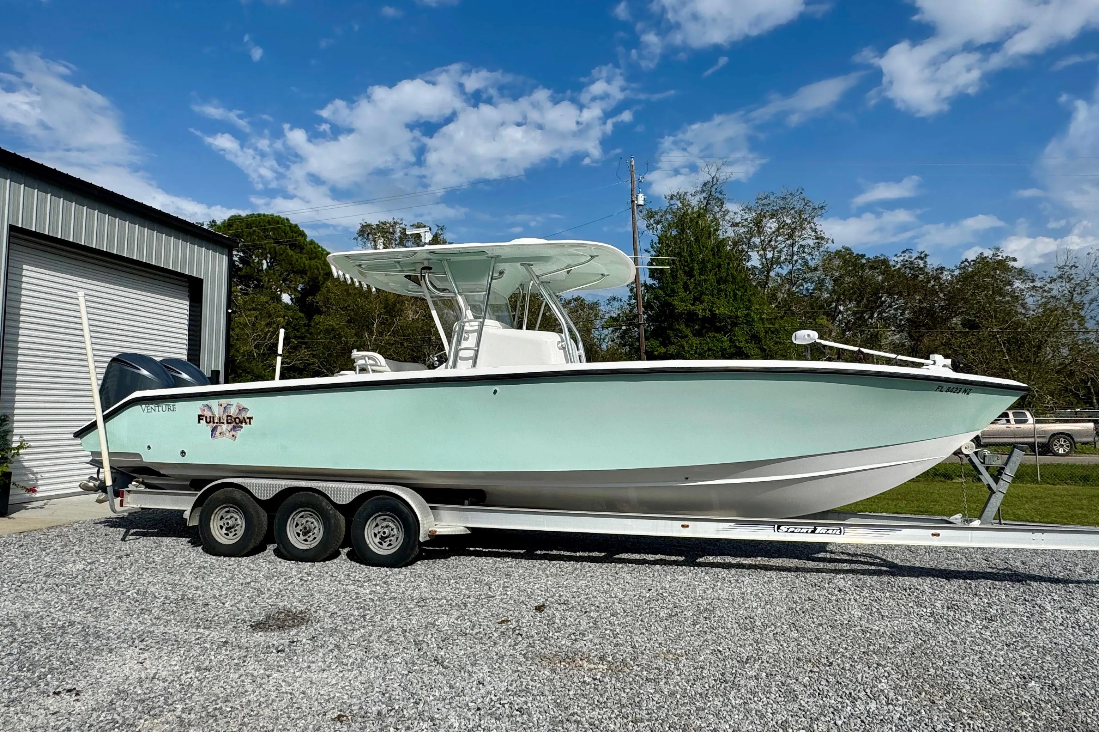 2010 Venture 34 Tournament boat on trailer, parked outdoors under blue sky.