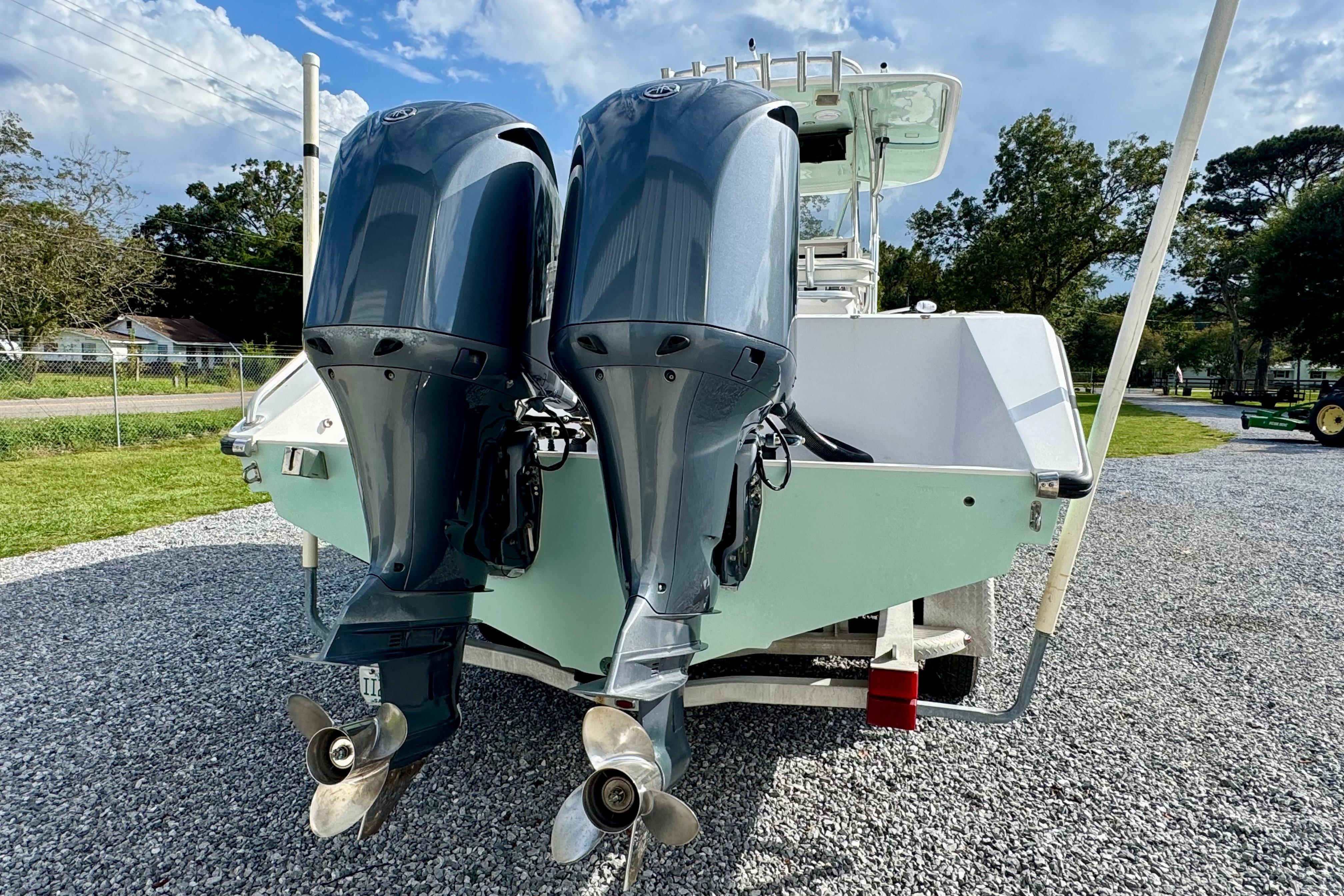 2010 Venture 34 Tournament boat with dual outboard motors on gravel driveway.