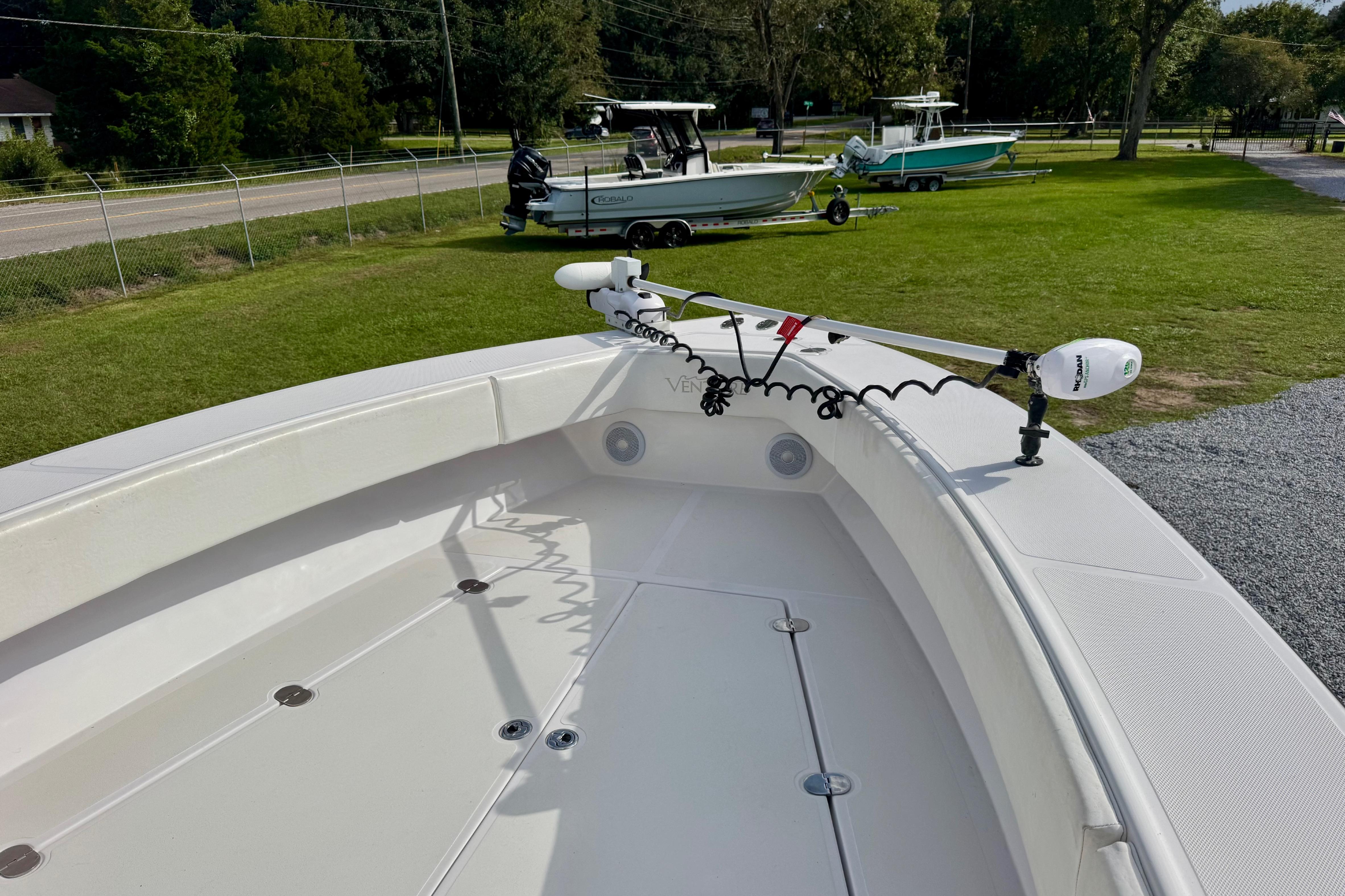 2010 Venture 34 Tournament boat with trolling motor on deck, parked on grass.