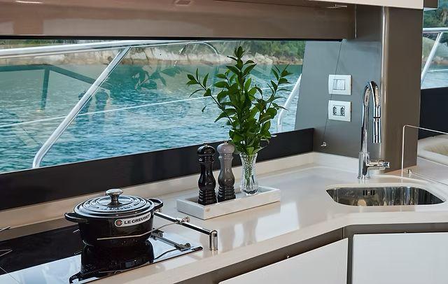 Modern yacht kitchen interior with sleek design, featuring a Le Creuset pot and scenic ocean view.