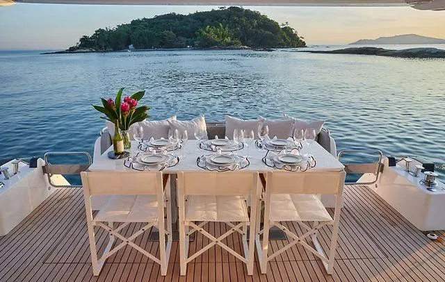  Yacht Photos Pics Luxury dining setup on Schaefer 660 yacht, 2025, with ocean view and island backdrop.
