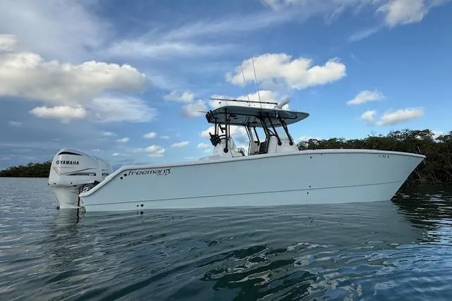  Yacht Photos Pics 2019 Freeman 34 boat on calm water with Yamaha engine, under a partly cloudy sky.