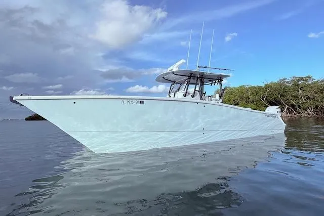  Yacht Photos Pics 2019 Freeman 34 boat on calm water, clear sky, and lush greenery in the background.