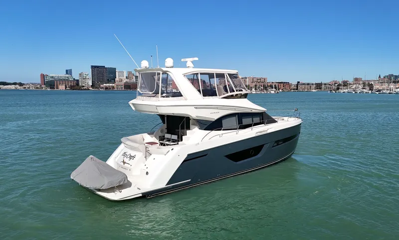 Play Craft Yacht Photos Pics 2018 Carver C52 Flybridge yacht on calm water with city skyline background.