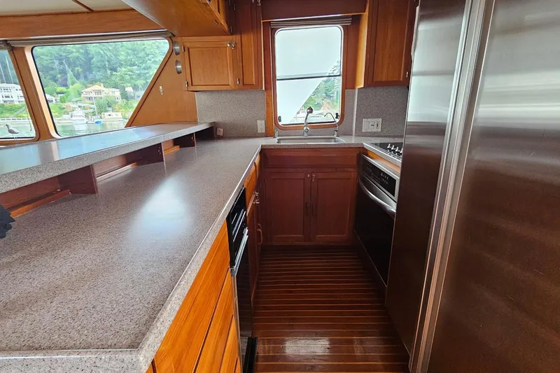  Yacht Photos Pics 1987 DeFever 53 POC yacht kitchen with wood cabinetry, stainless steel appliances, and large windows.