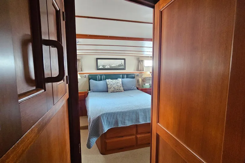  Yacht Photos Pics Cozy bedroom on 1987 DeFever 53 POC yacht with wooden interior and blue bedding.