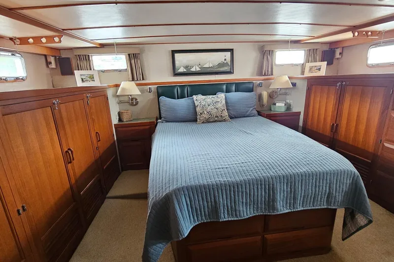  Yacht Photos Pics Luxurious 1987 DeFever 53 POC yacht bedroom with elegant wood cabinetry and cozy bedding.