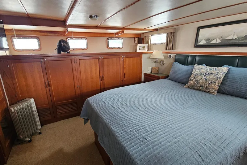  Yacht Photos Pics Luxurious 1987 DeFever 53 POC yacht bedroom with wood cabinets and blue bedding.