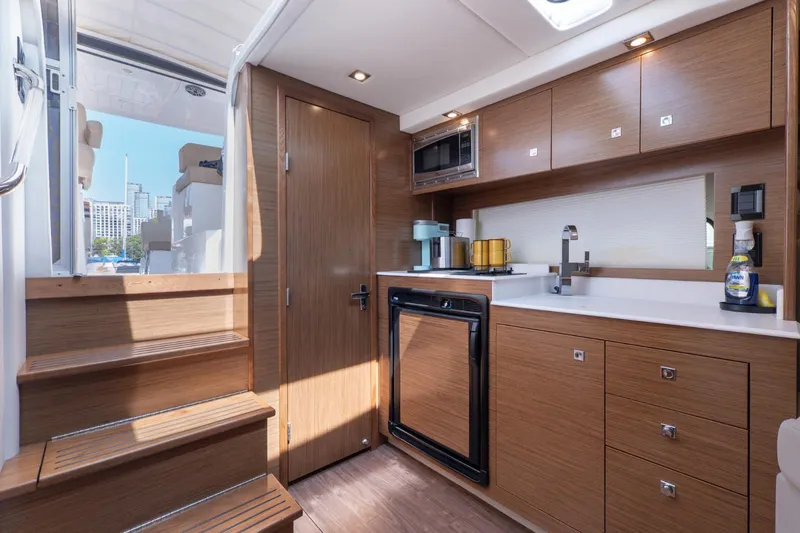  Yacht Photos Pics 2016 Cruisers Yachts 390 Express Coupe interior kitchen with wood cabinetry and modern appliances.