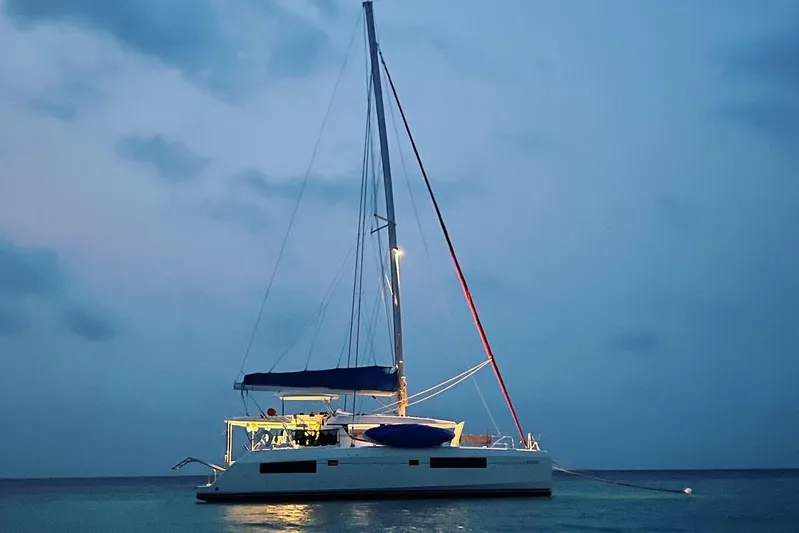 Nice Aft Too Yacht Photos Pics 2018 Leopard 45 catamaran illuminated at dusk on calm waters.