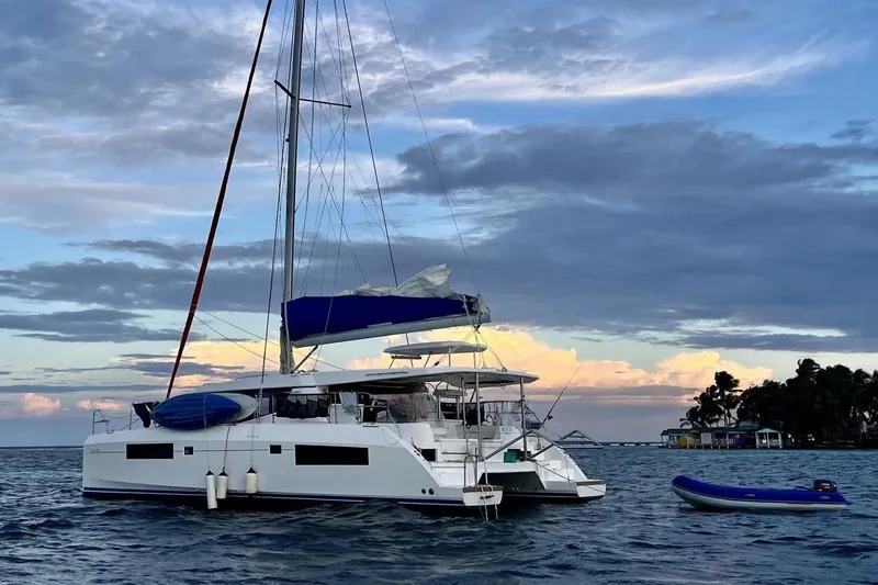 Nice Aft Too Yacht Photos Pics 2018 Leopard 45 catamaran anchored at sunset with inflatable boat nearby.
