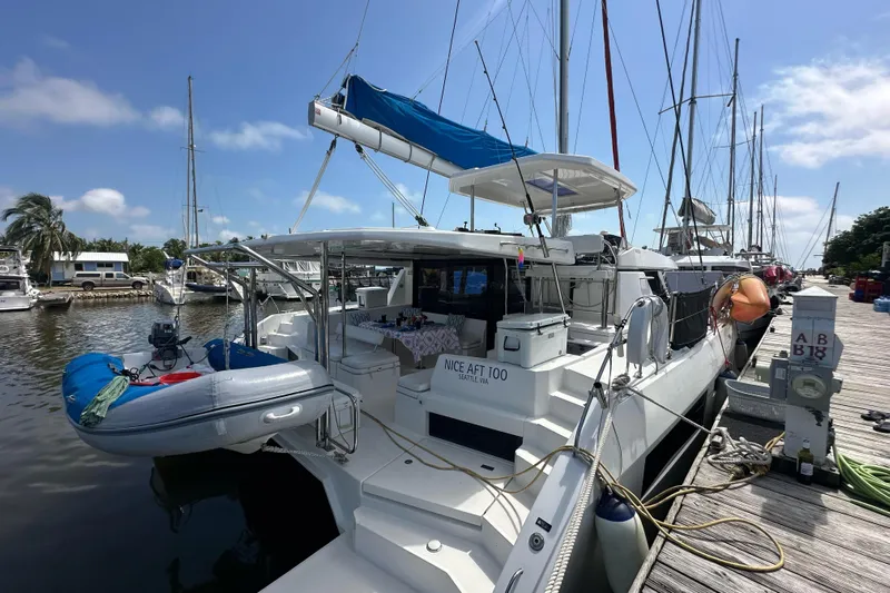 Nice Aft Too Yacht Photos Pics 2018 Leopard 45 catamaran docked at marina with inflatable dinghy and clear blue sky.