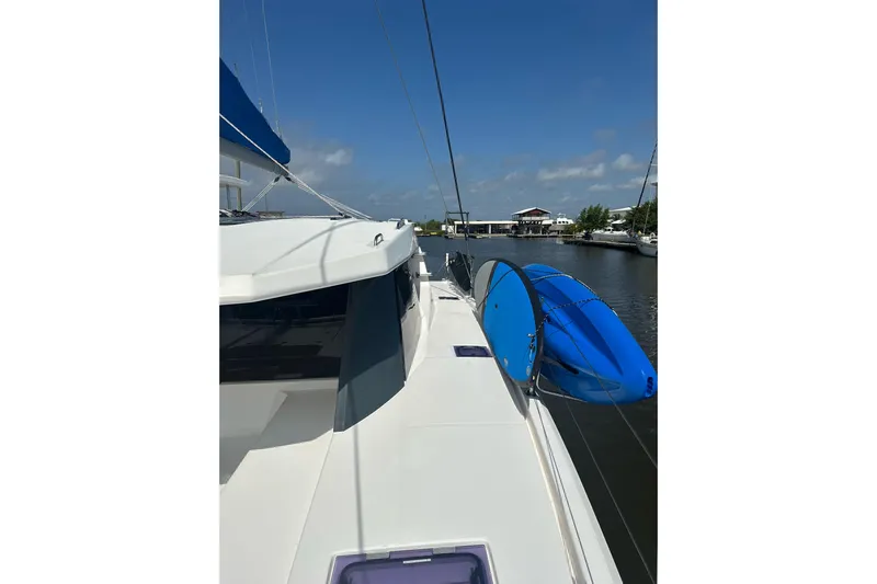 Nice Aft Too Yacht Photos Pics 2018 Leopard 45 catamaran with blue kayak on deck, docked in sunny marina.