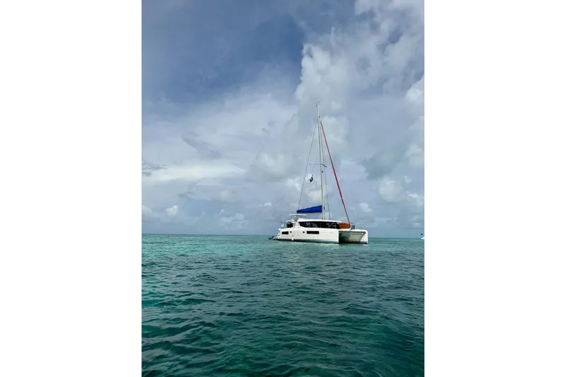Nice Aft Too Yacht Photos Pics 2018 Leopard 45 catamaran sailing on turquoise ocean under cloudy sky.