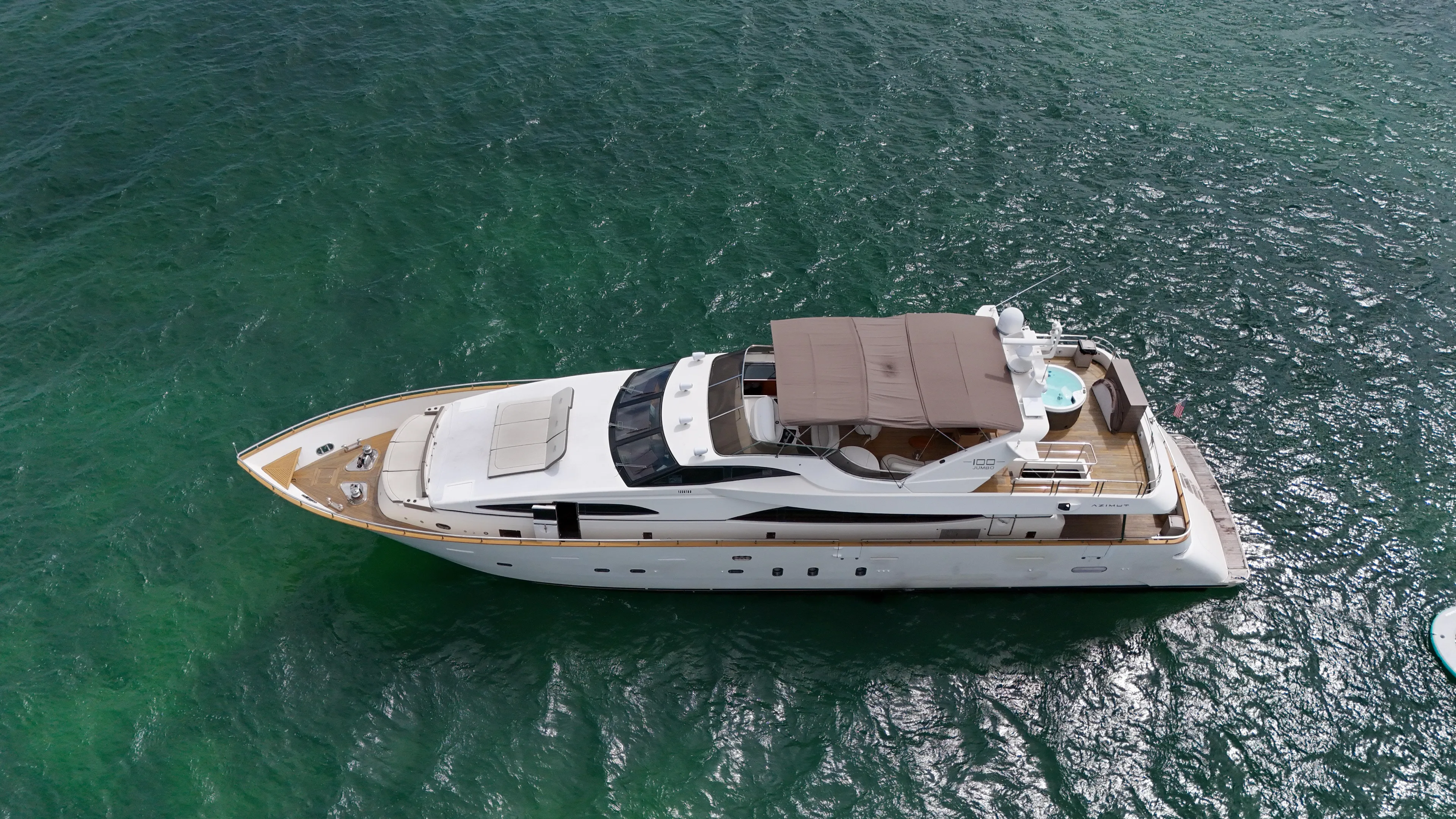  Yacht Photos Pics Aerial view of a 2006 Azimut 100 Jumbo yacht cruising on clear green waters.