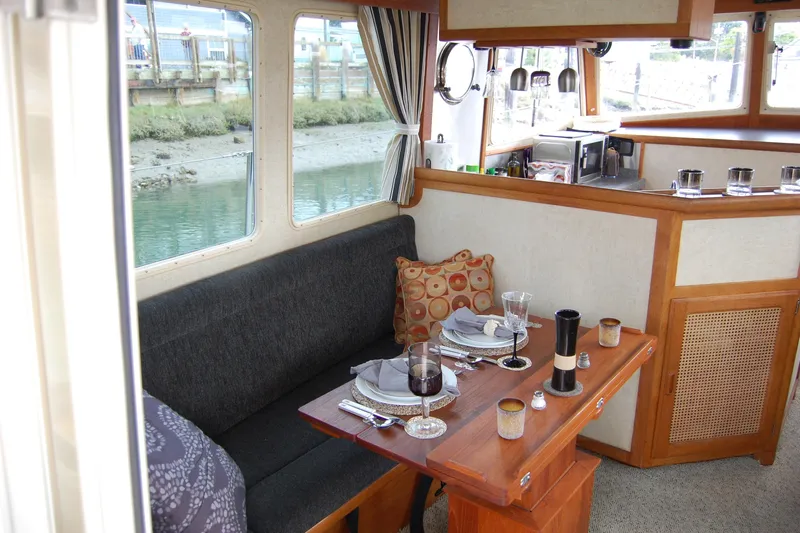  Yacht Photos Pics Cozy dining area inside a 1981 Willard Marine Pilot House Trawler, featuring elegant table settings.