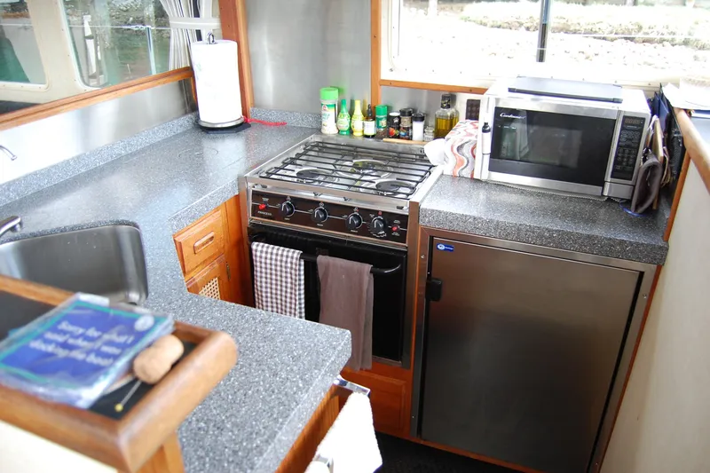  Yacht Photos Pics Compact kitchen in 1981 Willard Marine Pilot House Trawler with stove, microwave, and sink.
