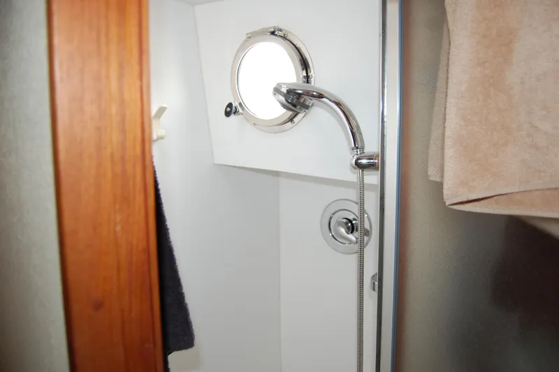  Yacht Photos Pics Shower area inside 1981 Willard Marine Pilot House Trawler, featuring a porthole and chrome fixtures.