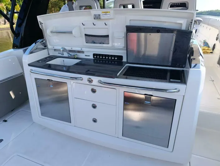  Yacht Photos Pics 2024 Boston Whaler 420 Outrage boat kitchen with sink, grill, and storage cabinets.
