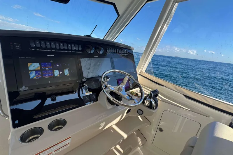True Story Yacht Photos Pics Boston Whaler 380 Realm 2022 helm with navigation screens, steering wheel, and ocean view.
