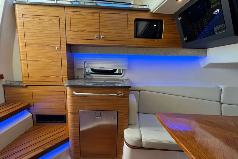 True Story Yacht Photos Pics 2022 Boston Whaler 380 Realm interior with wood cabinetry, seating, and ambient blue lighting.