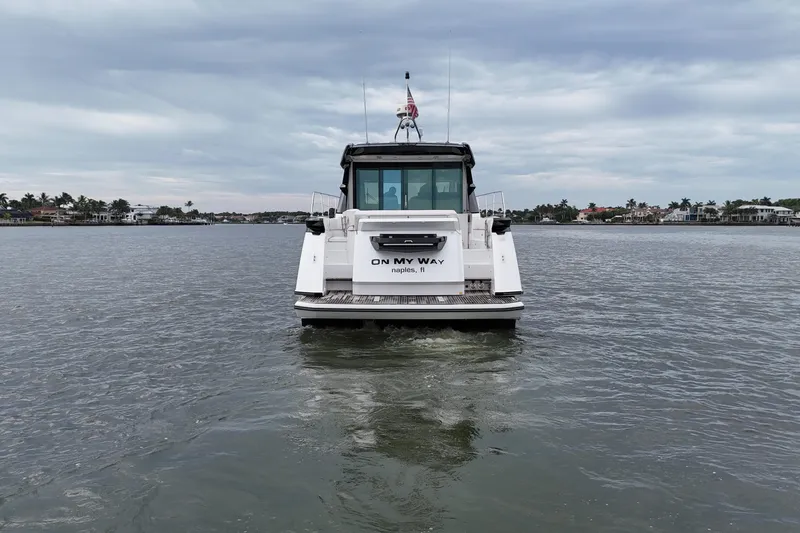 On My Way Yacht Photos Pics 2018 Beneteau Gran Turismo 50 yacht cruising on a calm waterway under cloudy skies.