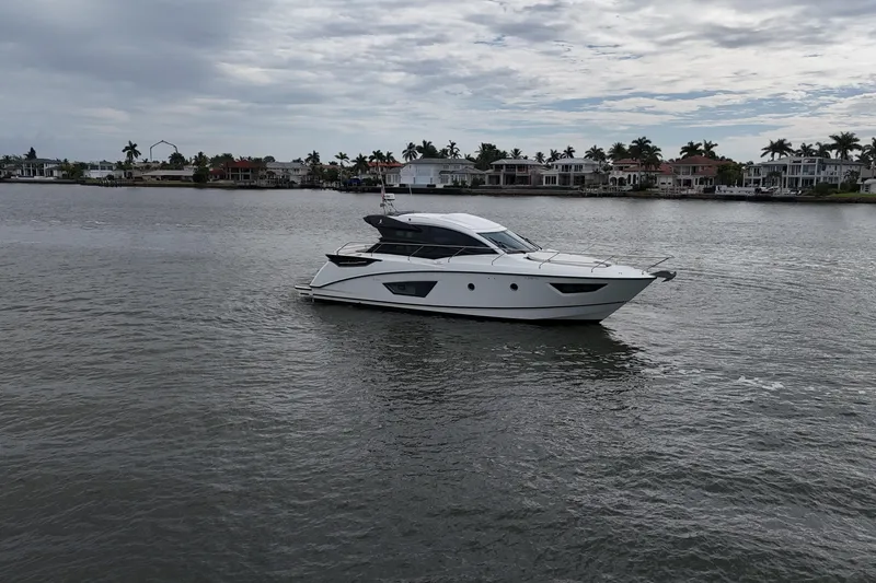 On My Way Yacht Photos Pics 2018 Beneteau Gran Turismo 50 yacht cruising on a calm waterway under cloudy skies.