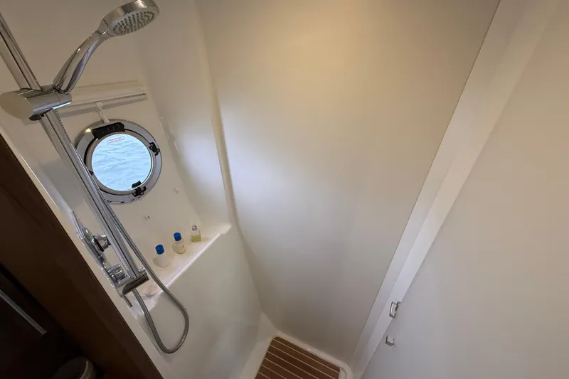 On My Way Yacht Photos Pics Shower area in 2018 Beneteau Gran Turismo 50 yacht with porthole and modern fixtures.
