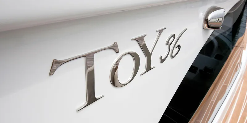  Yacht Photos Pics Close-up of Toy 36 yacht emblem, 2025 model, on sleek white surface.