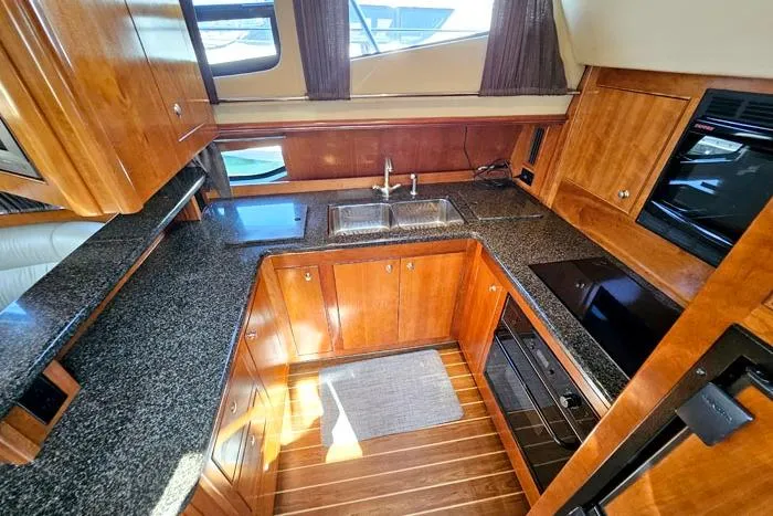  Yacht Photos Pics Luxurious 2006 Cruisers Yachts 455 Express Motoryacht kitchen with wood cabinetry and modern appliances.