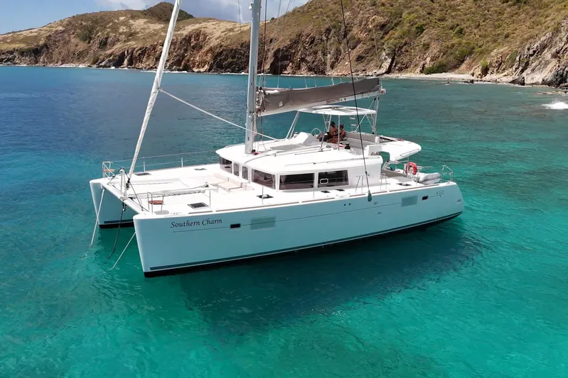  Yacht Photos Pics 2015 Lagoon 450 catamaran "Southern Charm" anchored in clear turquoise waters near rocky coastline.