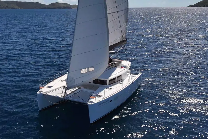  Yacht Photos Pics Sailing Lagoon 450 catamaran from 2015 on open sea with scenic coastline.