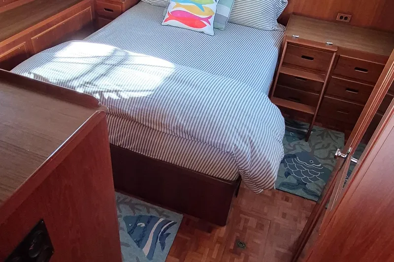 Lan Mara Yacht Photos Pics Cozy bedroom in 1987 Grand Banks 42 Classic Trawler with striped bedding and wooden cabinetry.