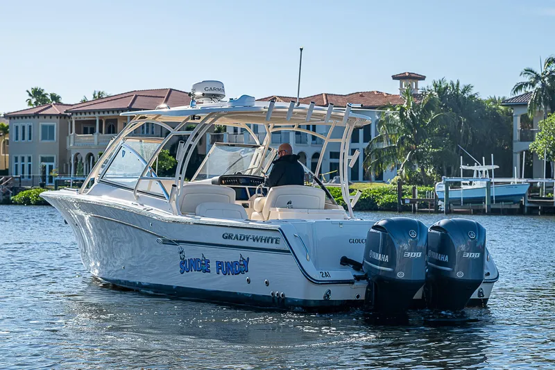 Sundae Funday Yacht Photos Pics 2017 Grady-White Freedom 307 boat cruising on a sunny waterfront with luxury homes.