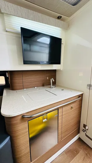 Twin J Yacht Photos Pics 2021 Boston Whaler 420 Outrage interior with modern kitchenette and mounted TV.