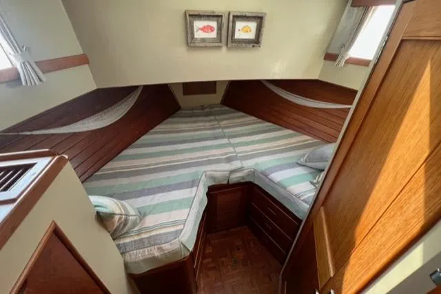 Lan Mara Yacht Photos Pics 1987 Grand Banks 42 Classic Trawler cabin with striped bedding and wooden interior.