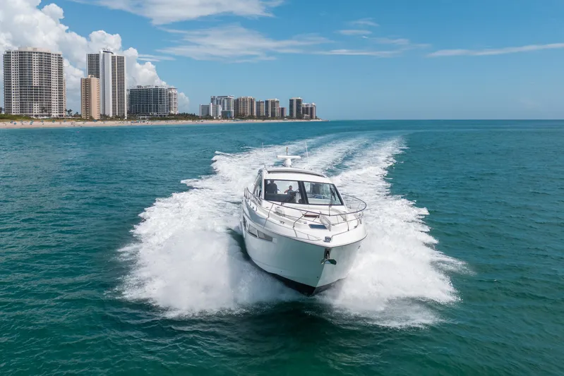 Risky Business Yacht Photos Pics 2019 Cruisers Yachts Cantius speeding on ocean near city skyline.