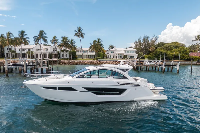 Risky Business Yacht Photos Pics 2019 Cruisers Yachts Cantius on water near luxury waterfront homes and palm trees.