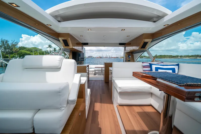 Risky Business Yacht Photos Pics Luxurious 2019 Cruisers Yachts Cantius interior with white seating and wooden accents, overlooking the water.